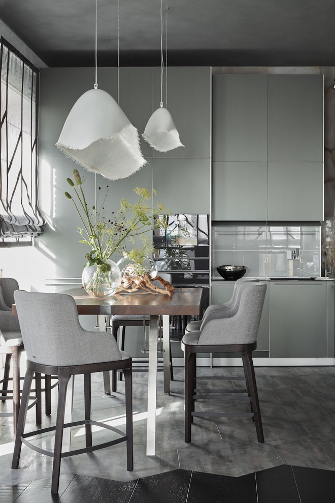 Imagen de cocina contemporánea con armarios con paneles lisos, puertas de armario grises, salpicadero verde, electrodomésticos negros y suelo gris