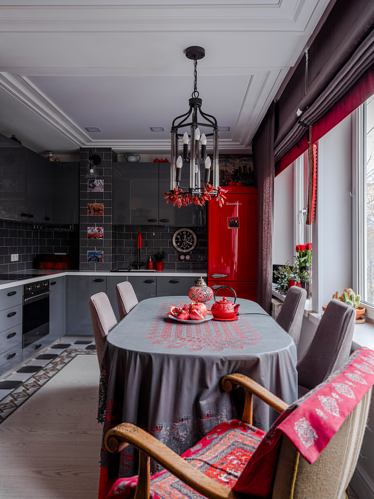 Foto di una cucina a L eclettica con ante lisce, ante grigie, paraspruzzi grigio, elettrodomestici neri e top bianco