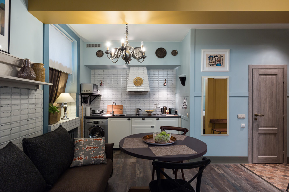 Свежая идея для дизайна: маленькая кухня-гостиная в стиле фьюжн с полом из керамической плитки и белыми фасадами без острова для на участке и в саду - отличное фото интерьера