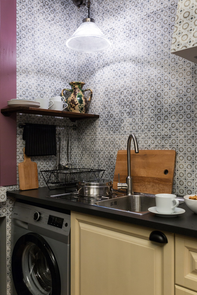 На фото: маленькая прямая кухня со стиральной машиной в стиле фьюжн с обеденным столом, фасадами с выступающей филенкой, желтыми фасадами, разноцветным фартуком, фартуком из керамической плитки и техникой из нержавеющей стали для на участке и в саду