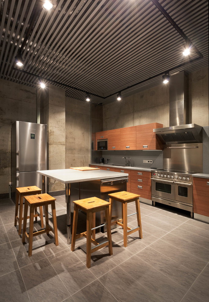 Photo of a large industrial single-wall enclosed kitchen in Moscow with a submerged sink, flat-panel cabinets, medium wood cabinets, engineered stone countertops, grey splashback, stone slab splashback, stainless steel appliances, porcelain flooring, an island and grey floors.