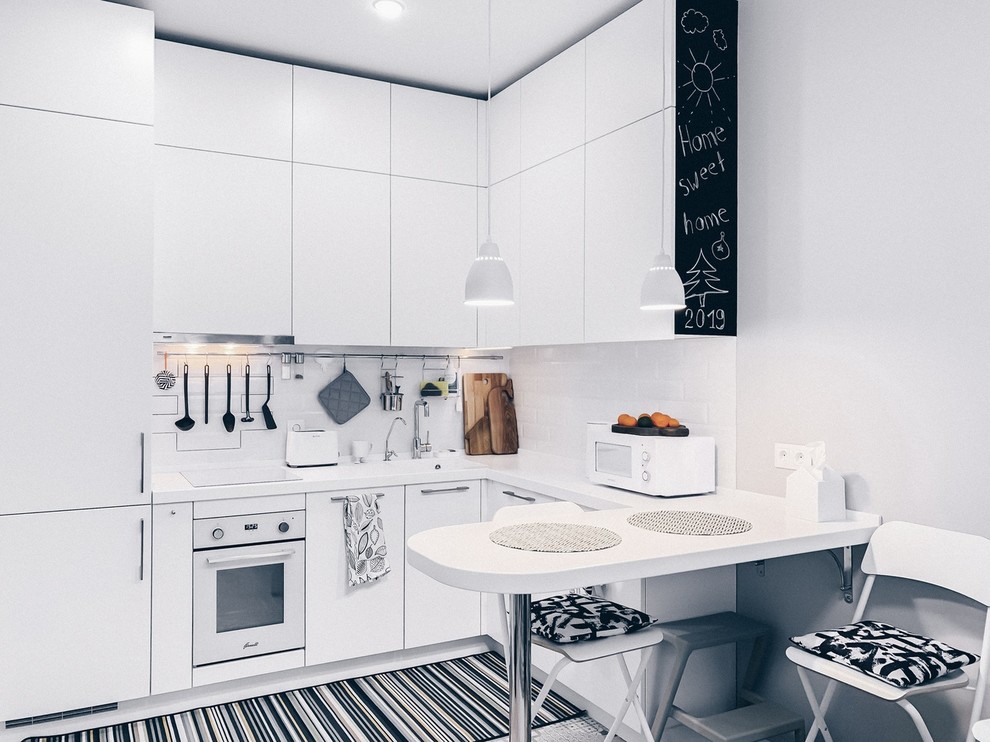 Inspiration för ett litet skandinaviskt vit vitt kök, med en integrerad diskho, släta luckor, vita skåp, vitt stänkskydd och vita vitvaror