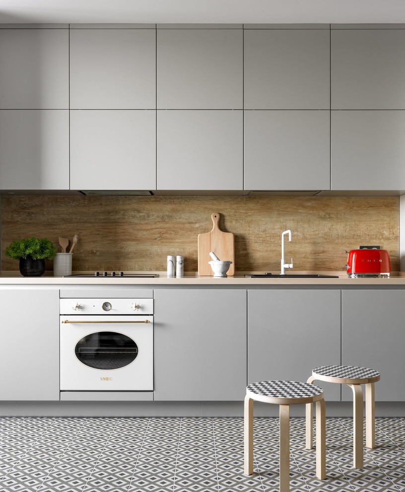 Modern inredning av ett beige beige kök, med släta luckor, grå skåp, beige stänkskydd, vita vitvaror och flerfärgat golv