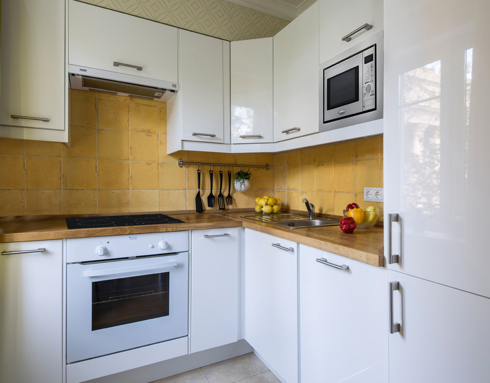 Пример оригинального дизайна: кухня-гостиная в скандинавском стиле с накладной мойкой, плоскими фасадами, белыми фасадами, желтым фартуком и белой техникой без острова