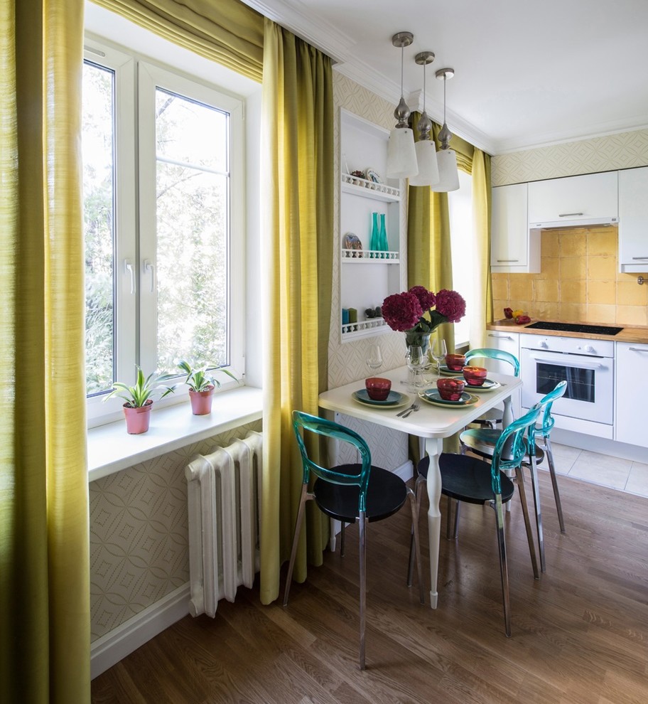 Offene Nordische Küche ohne Insel in L-Form mit flächenbündigen Schrankfronten, weißen Schränken, Küchenrückwand in Gelb, weißen Elektrogeräten und braunem Holzboden in Moskau