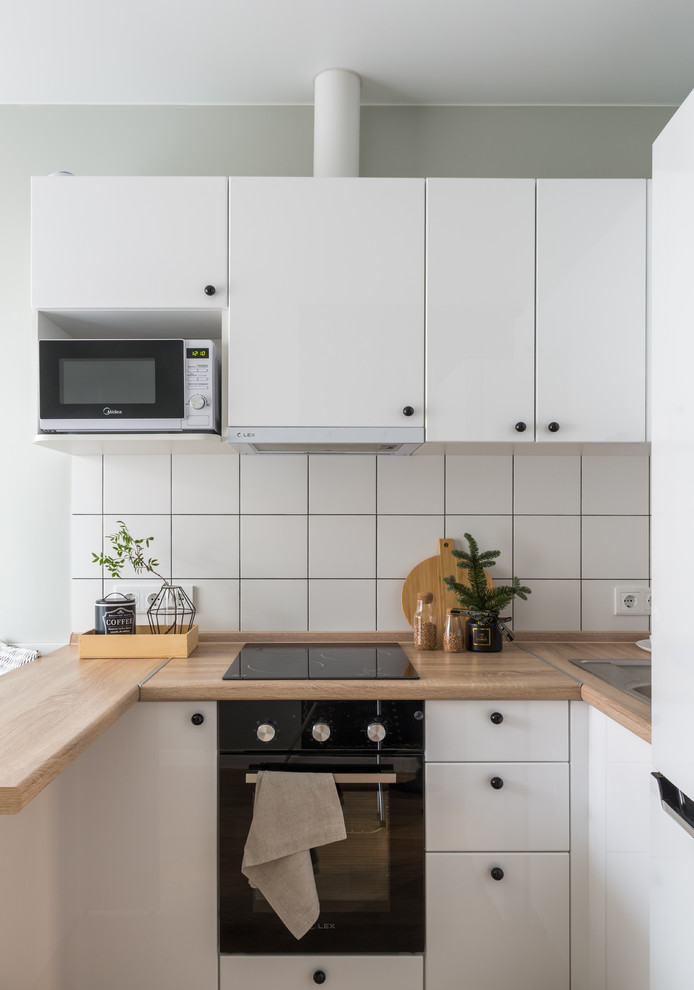 Inspiration for a small scandinavian u-shaped eat-in kitchen remodel in Other with a drop-in sink, flat-panel cabinets, white cabinets, wood countertops, white backsplash, a peninsula and beige countertops
