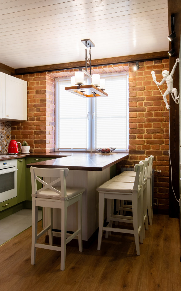 Inspiration for a small classic l-shaped kitchen in Moscow with flat-panel cabinets, green cabinets, wood worktops, white appliances, medium hardwood flooring, a breakfast bar, brown floors, brown worktops and a wood ceiling.