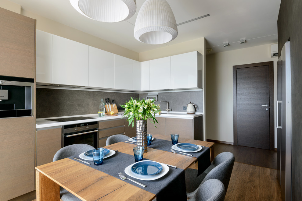 Photo of a contemporary u-shaped enclosed kitchen in Novosibirsk with flat-panel cabinets, light wood cabinets, grey splashback, stainless steel appliances, dark hardwood flooring, no island, brown floors and white worktops.