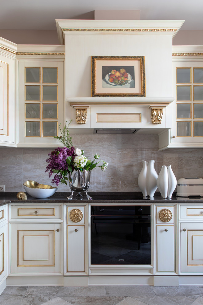Klassische Küche mit profilierten Schrankfronten, weißen Schränken, Küchenrückwand in Grau, schwarzen Elektrogeräten, grauem Boden und schwarzer Arbeitsplatte in Sonstige
