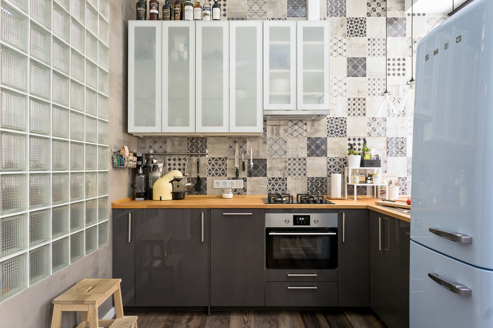 Kleine Moderne Wohnküche ohne Insel in L-Form mit flächenbündigen Schrankfronten, grauen Schränken, Arbeitsplatte aus Holz, dunklem Holzboden, braunem Boden, Einbauwaschbecken, Küchenrückwand in Grau und Küchengeräten aus Edelstahl in Moskau