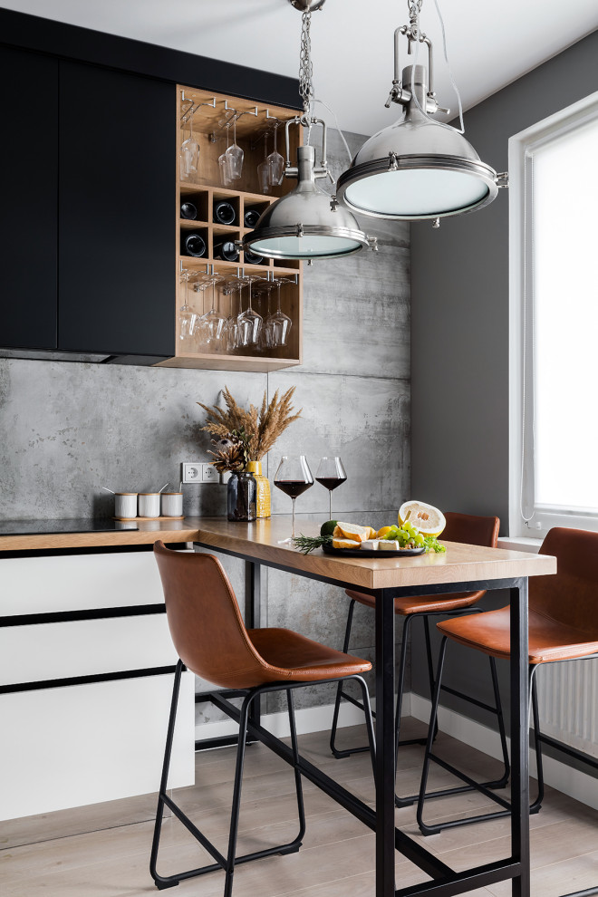 Photo of a small contemporary l-shaped kitchen/diner in Saint Petersburg with a submerged sink, flat-panel cabinets, black cabinets, wood worktops, grey splashback, porcelain splashback, black appliances, laminate floors, no island, beige floors and beige worktops.