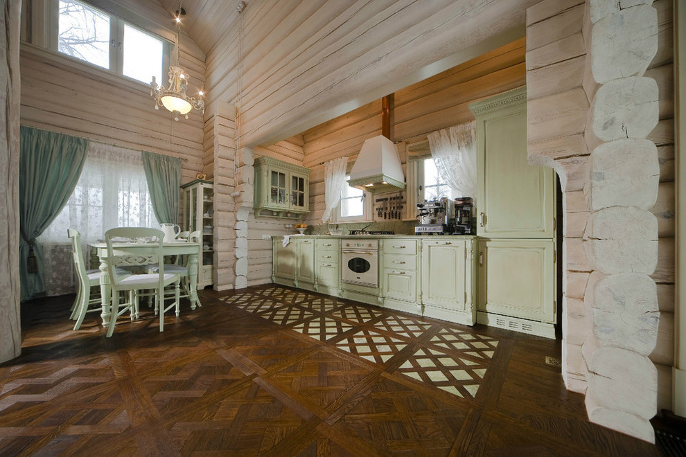 Lantlig inredning av ett stort linjärt kök, med en undermonterad diskho, luckor med upphöjd panel, gröna skåp, bänkskiva i onyx, vita vitvaror och mörkt trägolv