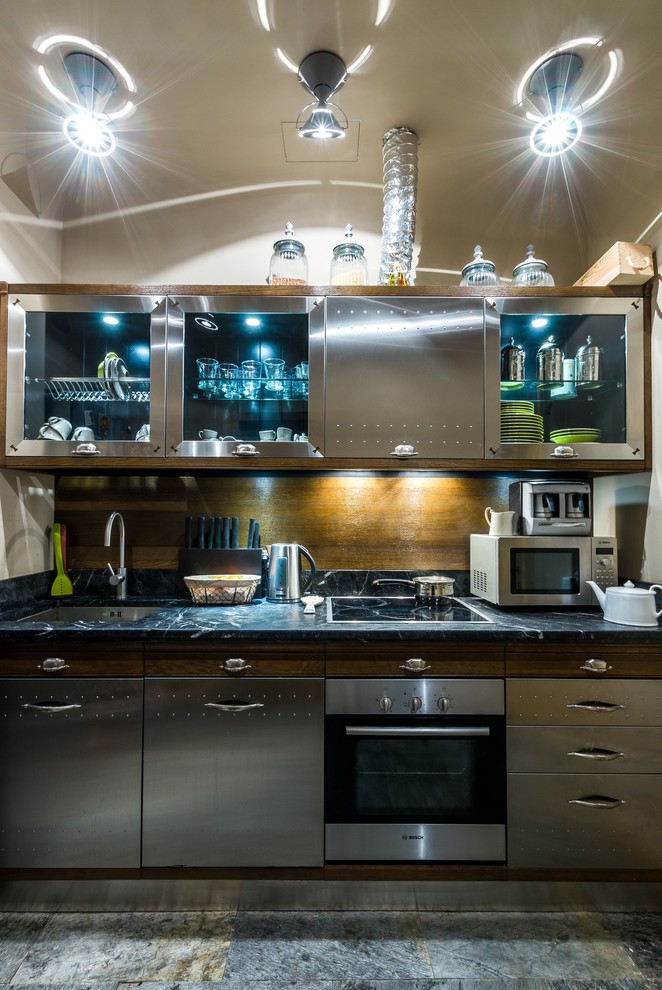 Modelo de cocina contemporánea con armarios con paneles lisos, puertas de armario en acero inoxidable, fregadero bajoencimera, salpicadero marrón y electrodomésticos de acero inoxidable