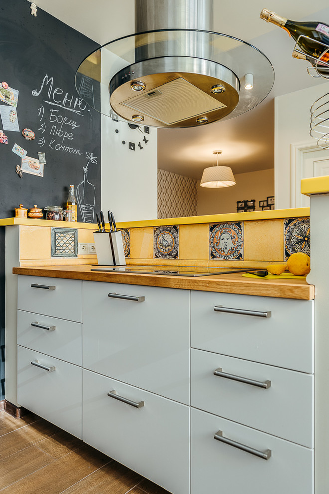 Diseño de cocina comedor escandinava pequeña con fregadero encastrado, armarios con paneles lisos, puertas de armario blancas, encimera de madera, salpicadero multicolor, salpicadero de azulejos de cerámica, electrodomésticos de acero inoxidable, suelo de madera en tonos medios, una isla, suelo marrón y encimeras marrones