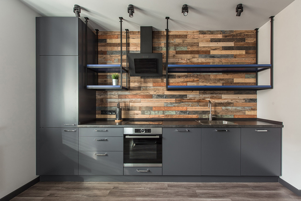 Foto de cocina lineal industrial con puertas de armario grises, salpicadero marrón, fregadero encastrado y armarios con paneles lisos