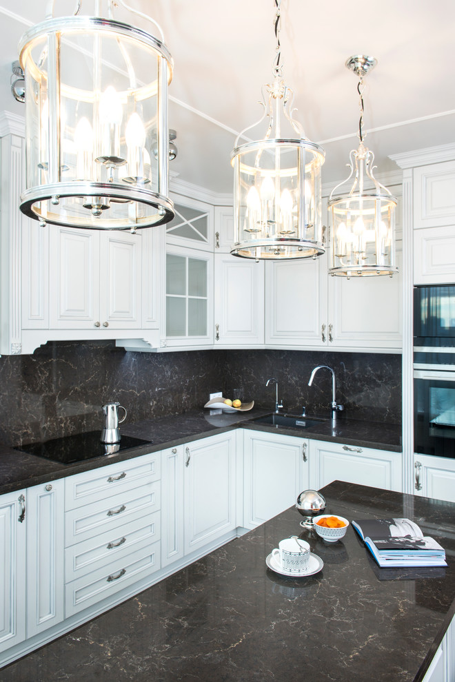 Стильный дизайн: угловая кухня-гостиная в классическом стиле с врезной мойкой, черным фартуком, черной техникой, островом и черно-белыми фасадами - последний тренд