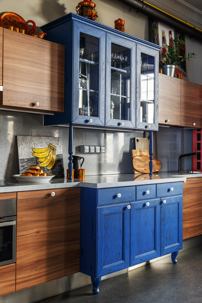 Пример оригинального дизайна: большая прямая кухня-гостиная в стиле фьюжн с серым полом, синими фасадами, столешницей из акрилового камня, серым фартуком, техникой из нержавеющей стали, островом и фасадами с утопленной филенкой