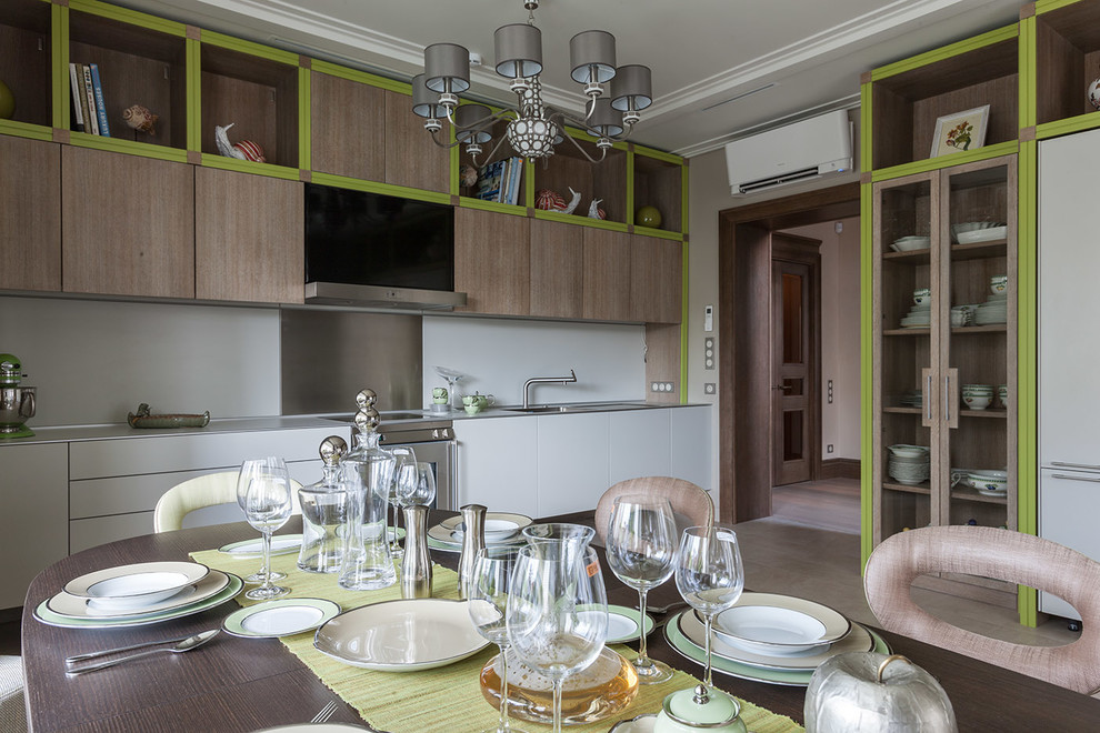 Foto på ett funkis linjärt kök och matrum, med släta luckor, rostfria vitvaror, skåp i ljust trä och stänkskydd med metallisk yta