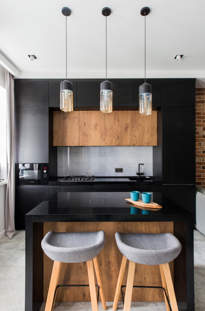 Стильный дизайн: параллельная кухня в стиле лофт с плоскими фасадами, черными фасадами, черной техникой, островом, серым полом и черной столешницей - последний тренд