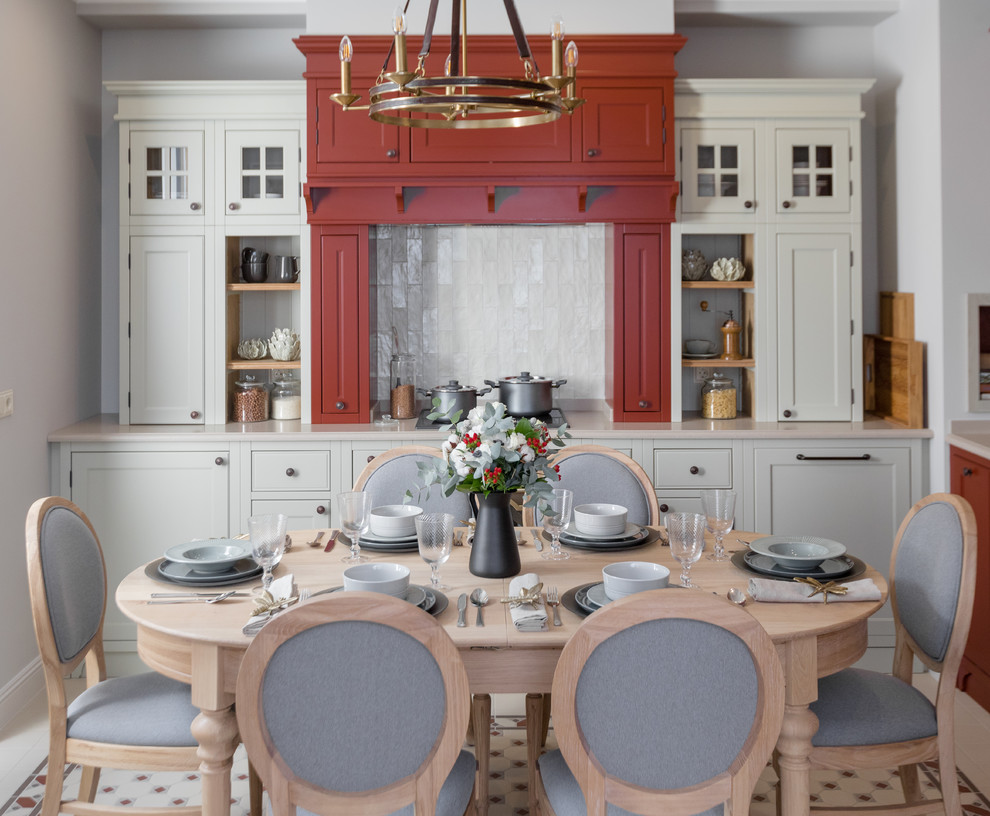 Modelo de cocina comedor clásica con armarios con paneles empotrados, puertas de armario rojas, salpicadero beige, suelo multicolor y encimeras beige