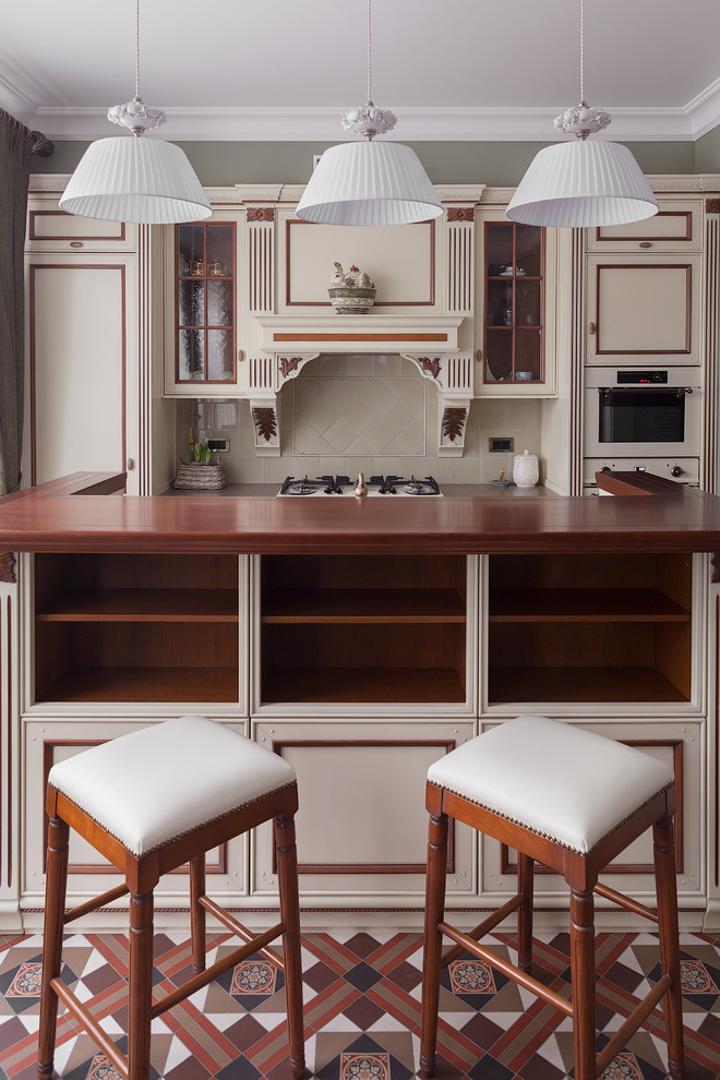Bild på ett vintage kök, med luckor med upphöjd panel, vita skåp, träbänkskiva, beige stänkskydd, stänkskydd i keramik, integrerade vitvaror, klinkergolv i keramik och en köksö