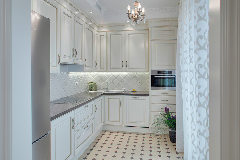 Immagine di una cucina a L classica con lavello da incasso, ante bianche, paraspruzzi bianco, elettrodomestici in acciaio inossidabile e nessuna isola