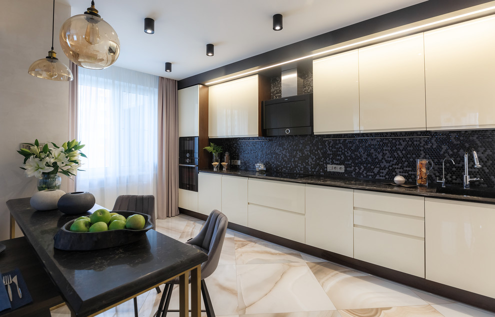 Ispirazione per una cucina design di medie dimensioni con lavello a vasca singola, ante lisce, ante beige, top in superficie solida, paraspruzzi nero, paraspruzzi con piastrelle a mosaico, elettrodomestici neri, pavimento in gres porcellanato, pavimento beige e top nero