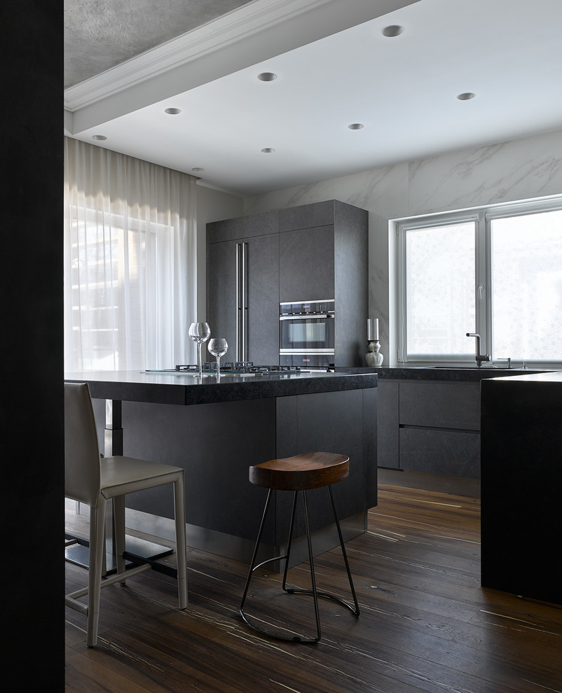 Источник вдохновения для домашнего уюта: угловая кухня-гостиная в современном стиле с плоскими фасадами, серыми фасадами, техникой из нержавеющей стали и островом