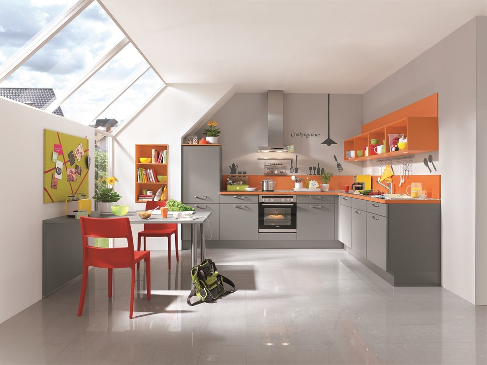 На фото: угловая кухня среднего размера в современном стиле с обеденным столом и оранжевым фартуком с