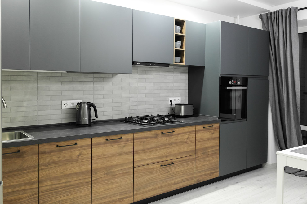 Photo of a medium sized urban l-shaped enclosed kitchen in Other with flat-panel cabinets, grey cabinets, laminate countertops, metro tiled splashback, black appliances, laminate floors, no island, grey floors, a single-bowl sink, beige splashback and grey worktops.