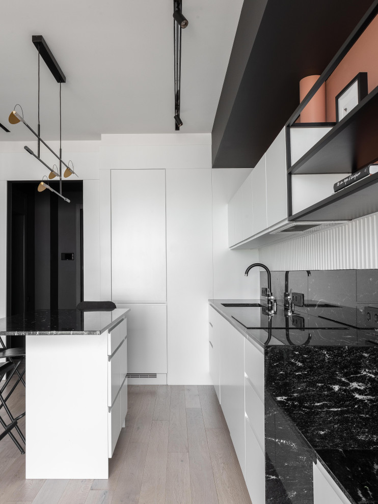 Exempel på ett litet minimalistiskt svart linjärt svart kök och matrum, med en undermonterad diskho, släta luckor, vita skåp, granitbänkskiva, svart stänkskydd, svarta vitvaror och en köksö