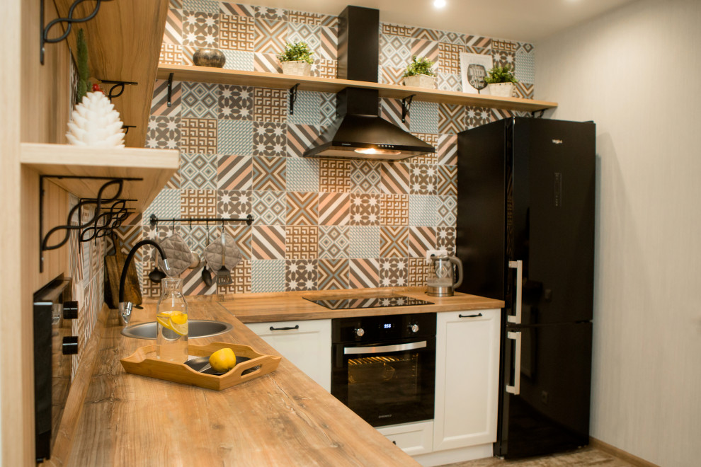 Inredning av ett nordiskt mellanstort brun brunt kök, med en undermonterad diskho, luckor med upphöjd panel, vita skåp, träbänkskiva, flerfärgad stänkskydd, stänkskydd i porslinskakel, integrerade vitvaror, klinkergolv i porslin och brunt golv