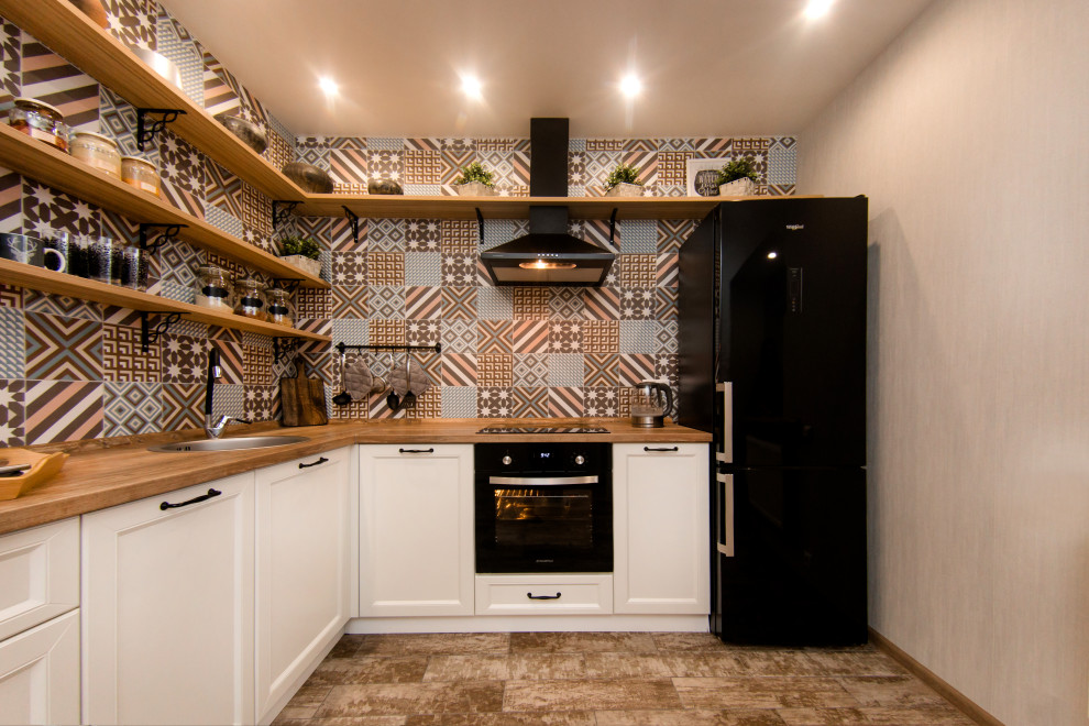 Eat-in kitchen - mid-sized scandinavian l-shaped ceramic tile and beige floor eat-in kitchen idea in Other with a drop-in sink, recessed-panel cabinets, white cabinets, wood countertops, multicolored backsplash, ceramic backsplash and black appliances