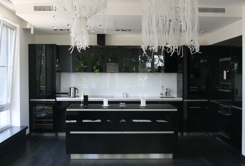 Bild på ett stort funkis kök, med en undermonterad diskho, luckor med glaspanel, svarta skåp, bänkskiva i kvarts, vitt stänkskydd, stänkskydd i glaskakel, svarta vitvaror, mörkt trägolv och en köksö