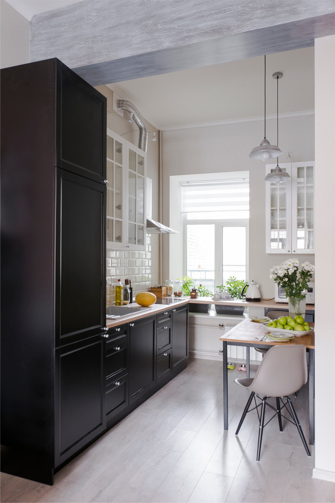 Inspiration for a small traditional single-wall kitchen/diner in Moscow with a submerged sink, black cabinets, white splashback, ceramic splashback, black appliances, medium hardwood flooring and no island.