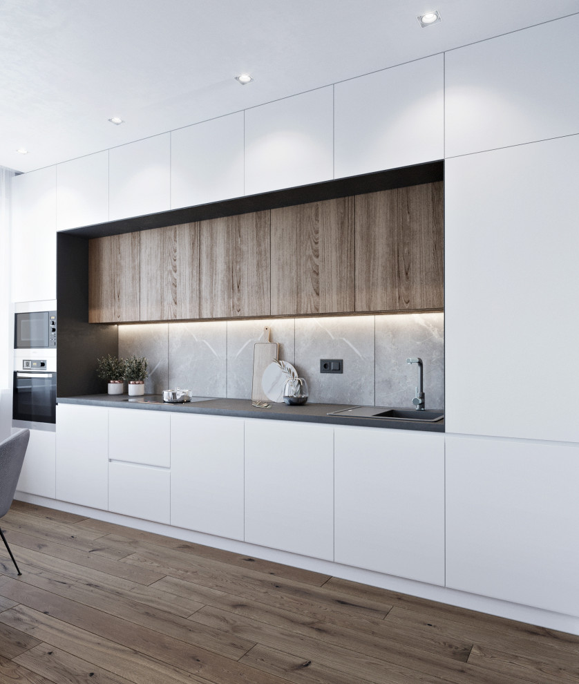 Medium sized contemporary single-wall open plan kitchen in Other with a built-in sink, flat-panel cabinets, white cabinets, composite countertops, grey splashback, ceramic splashback, stainless steel appliances, no island, brown floors, black worktops and ceramic flooring.