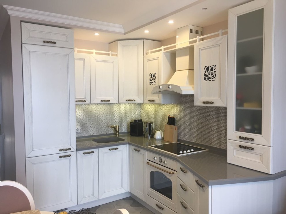Design ideas for a medium sized traditional l-shaped kitchen/diner in Saint Petersburg with an integrated sink, recessed-panel cabinets, white cabinets, composite countertops, mosaic tiled splashback, white appliances and ceramic flooring.