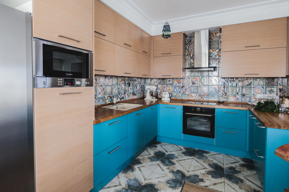 Стильный дизайн: п-образная кухня в современном стиле с накладной мойкой, плоскими фасадами, синими фасадами, деревянной столешницей, разноцветным фартуком и полуостровом - последний тренд