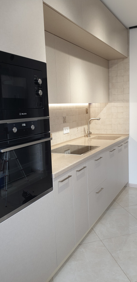 Inspiration for a small contemporary single-wall enclosed kitchen in Moscow with an integrated sink, flat-panel cabinets, beige cabinets, composite countertops, beige splashback, ceramic splashback, black appliances, porcelain flooring, no island, beige floors and beige worktops.