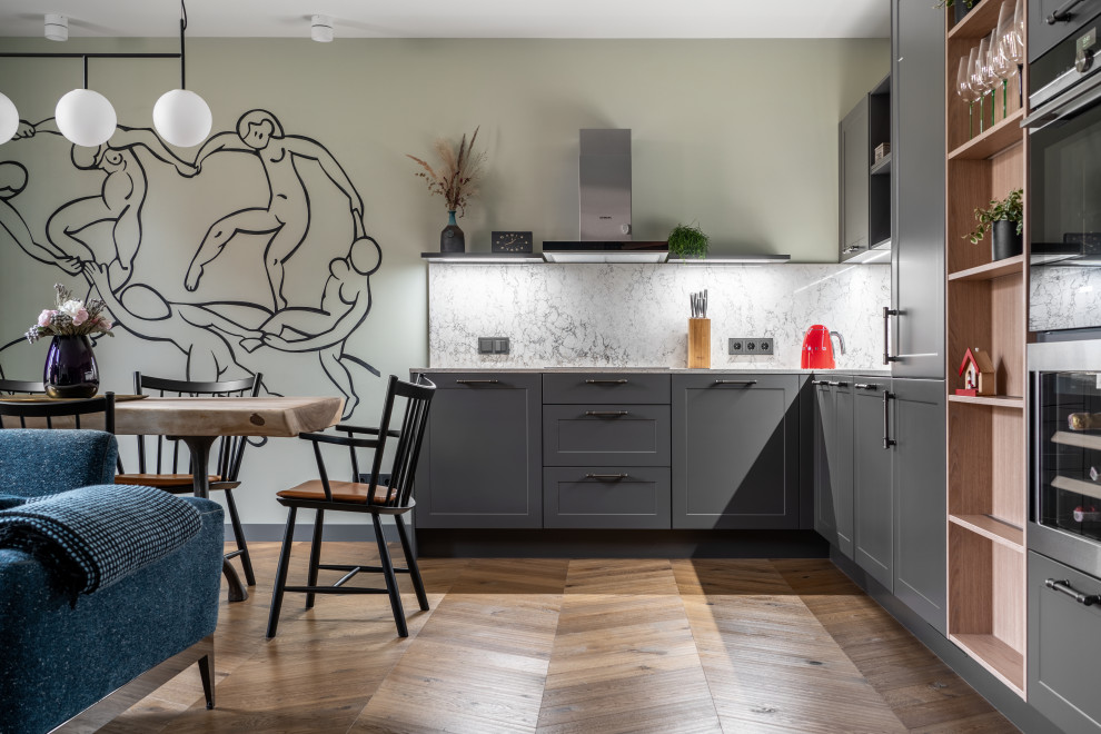 Modern inredning av ett stort grå grått kök, med en undermonterad diskho, luckor med infälld panel, grå skåp, bänkskiva i kvarts, grått stänkskydd, rostfria vitvaror, mellanmörkt trägolv och brunt golv