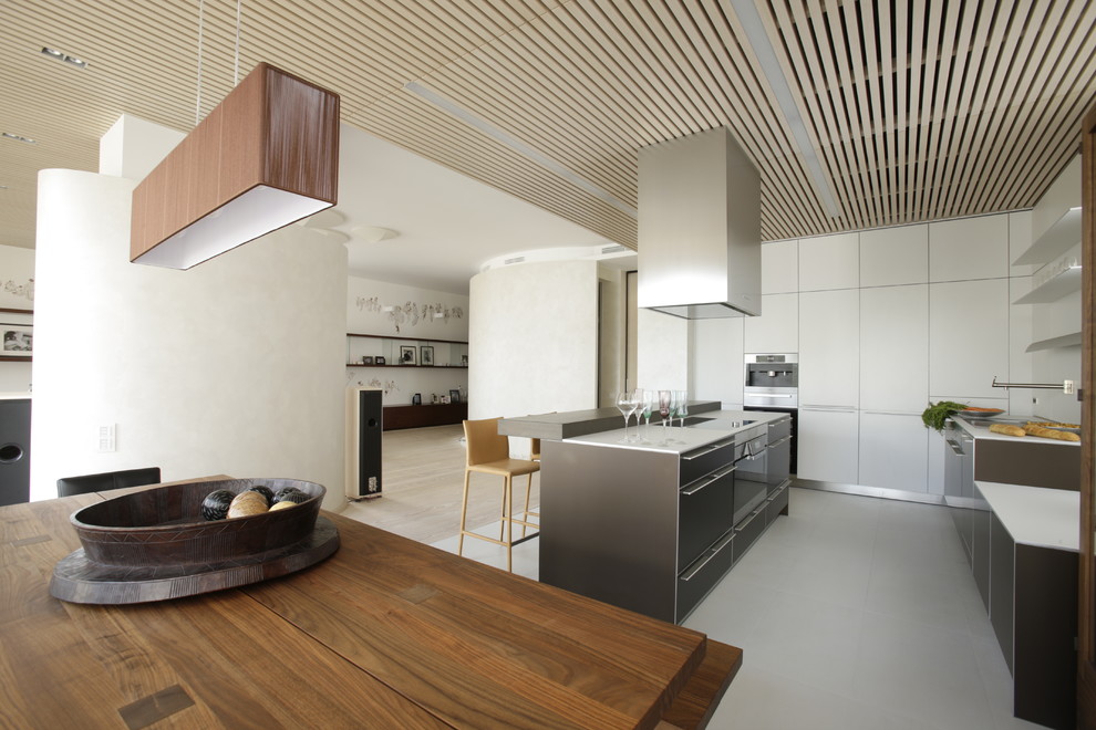 На фото: параллельная кухня-гостиная в современном стиле с плоскими фасадами, серыми фасадами и островом с