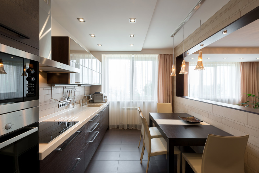 This is an example of a contemporary single-wall enclosed kitchen in Novosibirsk with flat-panel cabinets, dark wood cabinets, beige splashback and stainless steel appliances.