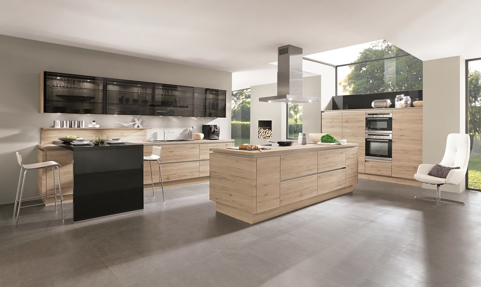 Cette image montre une grande cuisine parallèle design en bois clair avec un placard à porte plane et îlot.