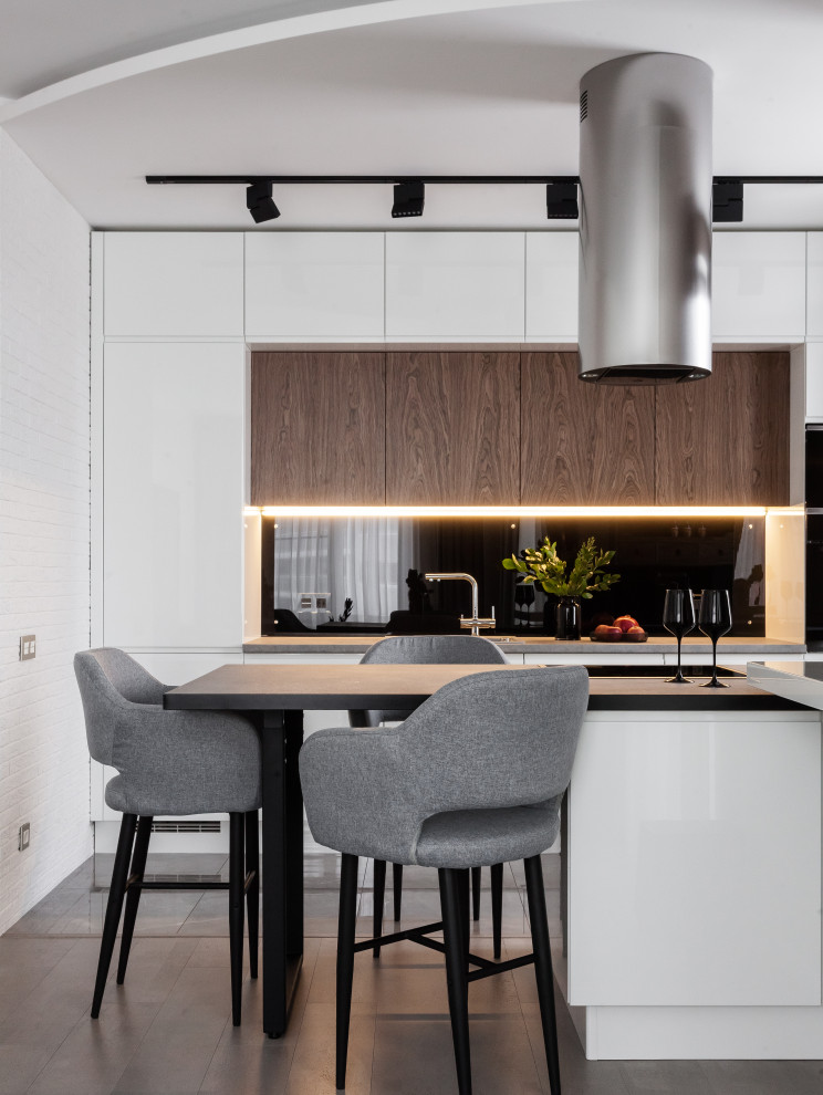 This is an example of a small contemporary galley kitchen in Other with a built-in sink, flat-panel cabinets, white cabinets, grey splashback, glass sheet splashback, integrated appliances, an island, grey floors and grey worktops.