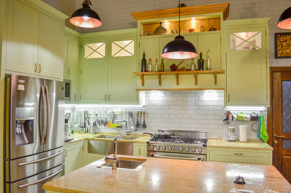 Inredning av ett klassiskt stort flerfärgad flerfärgat kök, med en dubbel diskho, skåp i shakerstil, gröna skåp, granitbänkskiva, vitt stänkskydd, stänkskydd i glaskakel, rostfria vitvaror, klinkergolv i terrakotta, en köksö och brunt golv