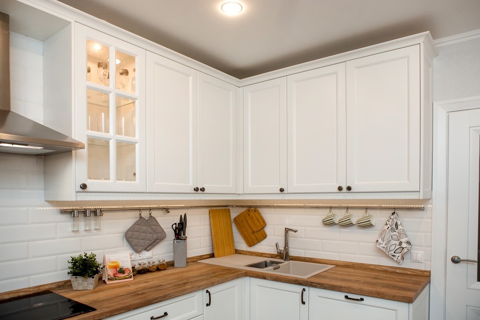 На фото: п-образная кухня среднего размера в скандинавском стиле с фасадами с утопленной филенкой и белыми фасадами