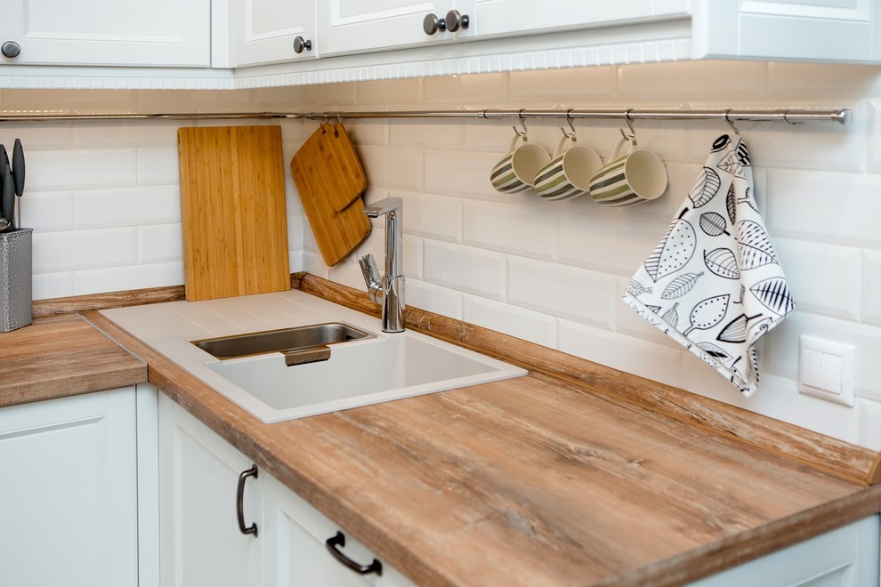 Réalisation d'une cuisine nordique en U de taille moyenne avec un placard avec porte à panneau encastré et des portes de placard blanches.