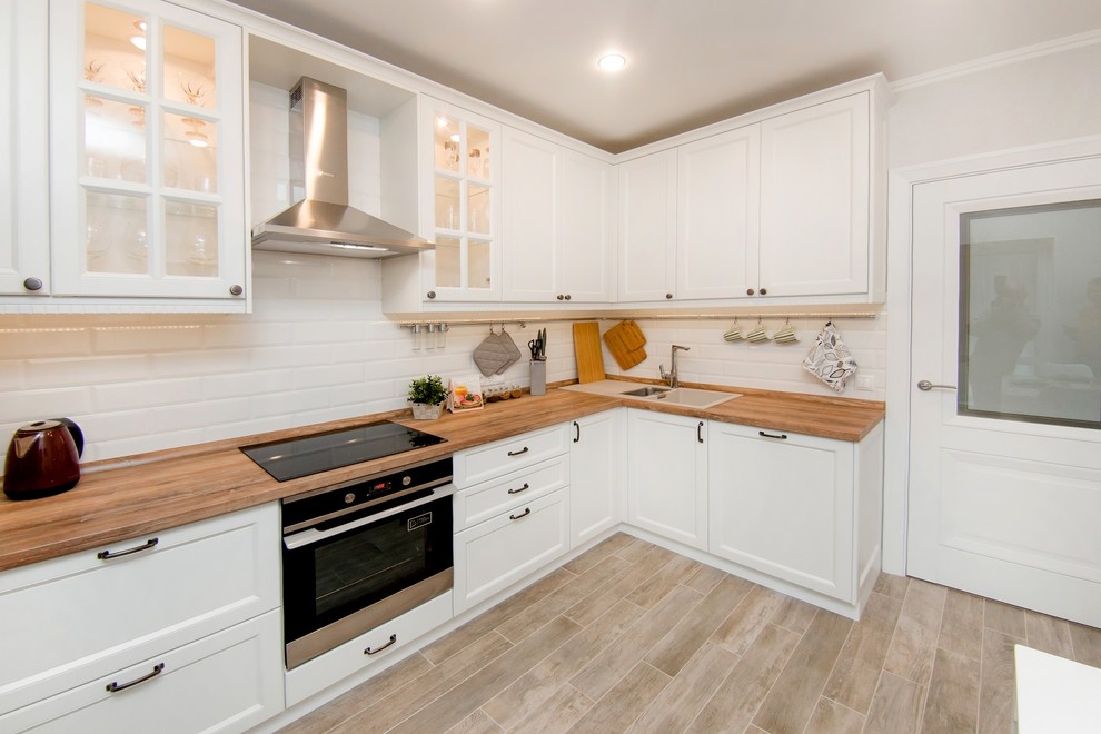 Medium sized scandinavian u-shaped kitchen in Other with recessed-panel cabinets and white cabinets.