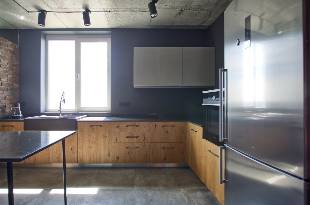 This is an example of a large industrial u-shaped open plan kitchen in Other with a belfast sink, flat-panel cabinets, medium wood cabinets, quartz worktops, grey splashback, stainless steel appliances, cement flooring, a breakfast bar, grey floors and grey worktops.