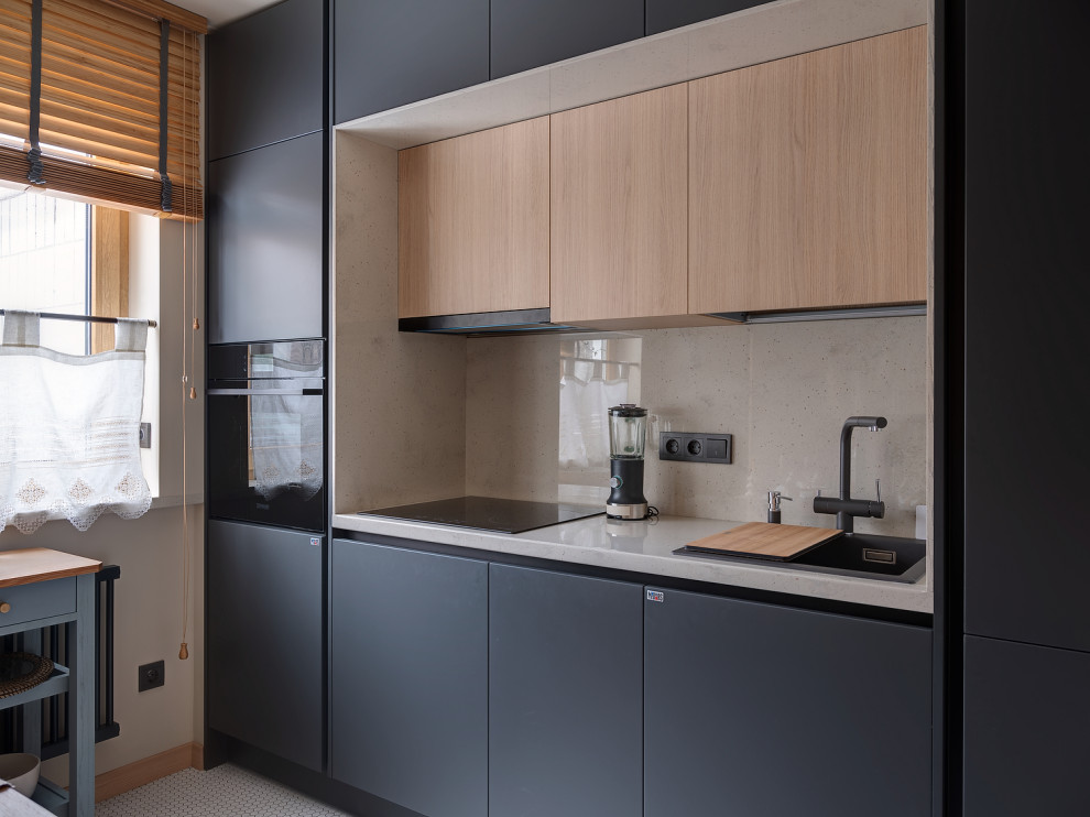На фото: кухня в современном стиле с накладной мойкой, плоскими фасадами, серыми фасадами, техникой из нержавеющей стали, белым полом и серой столешницей с